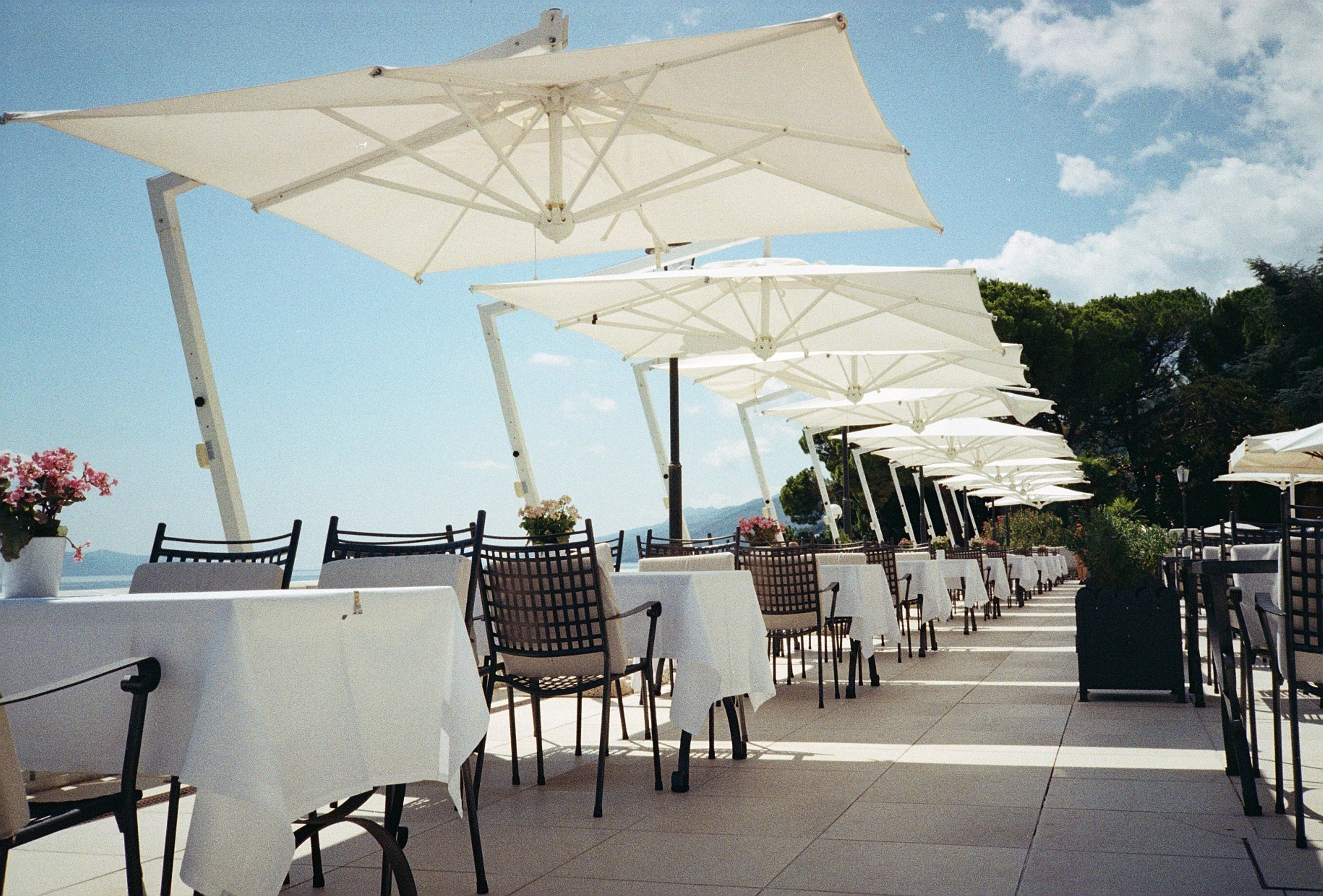 Oceanfront restaurant terrace with white umbrellas overlooking the sea